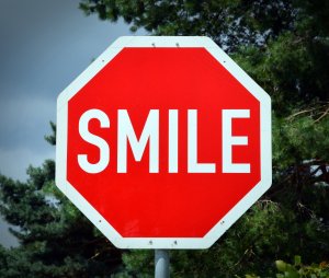 Eight sided red street sign that reads "SMILE."